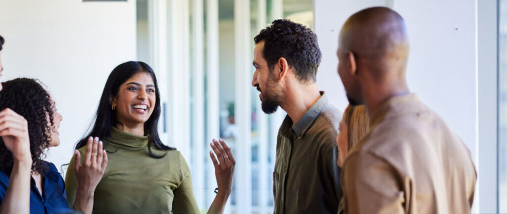 A joyful gathering of individuals engaged in conversation, sharing laughter, and displaying warm smiles.