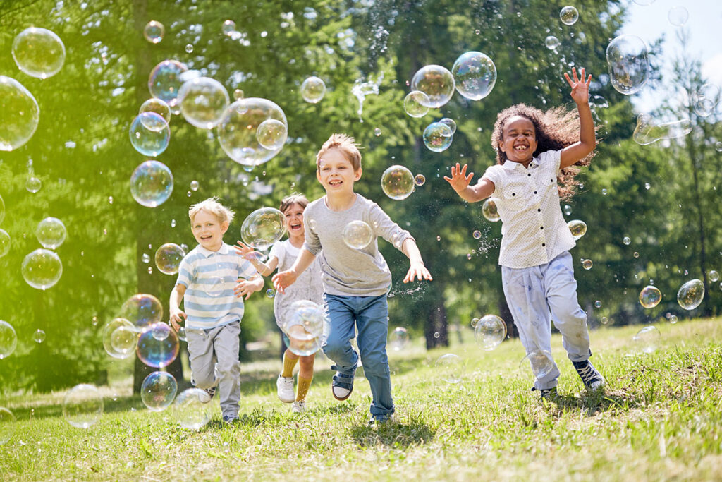 Children running through a field with bubbles